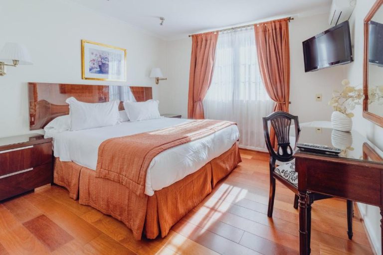 Habitación doble con cama matrimonial y suelos de madera en Orly Suites