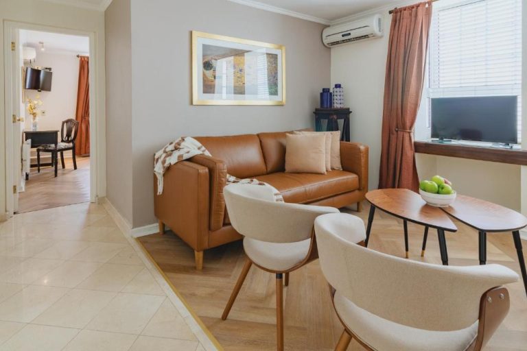 Salón elegante con sofá de cuero marrón y aire acondicionado en Orly Suites