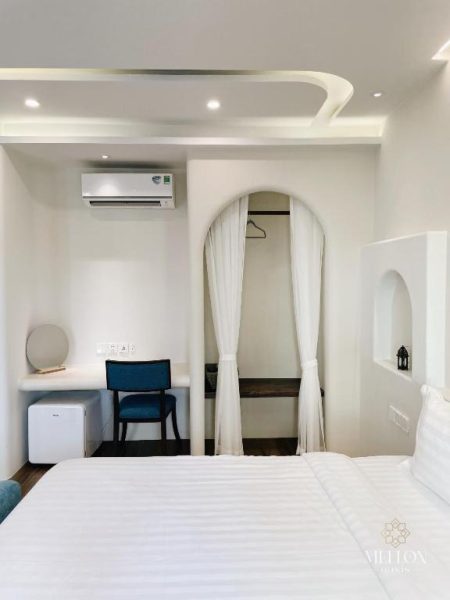 Habitación doble blanca con escritorio, armario y aire acondicionado en Mellon Oasis Phu Quoc