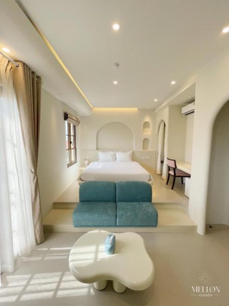 Habitación deluxe con cama doble y sofá azul turquesa en Mellon Oasis Phu Quoc