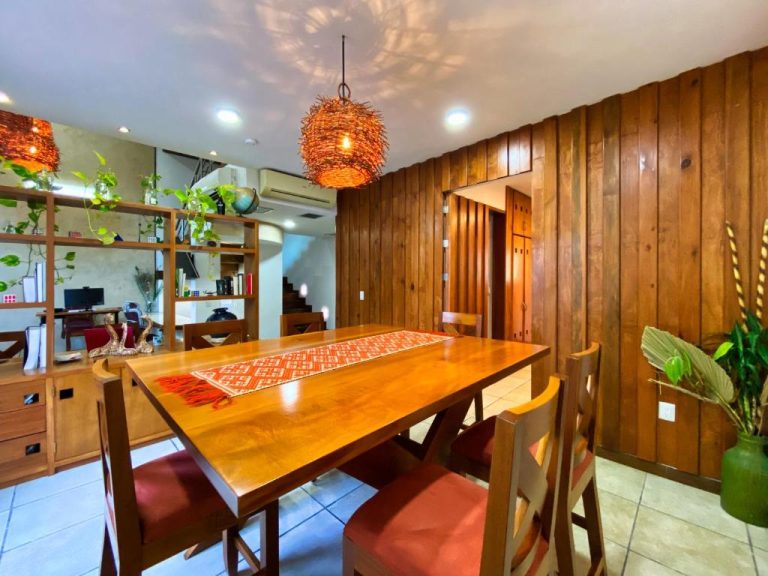 Comedor de madera con sillas rojas y lámpara artesanal en Humant Coliving Cancún
