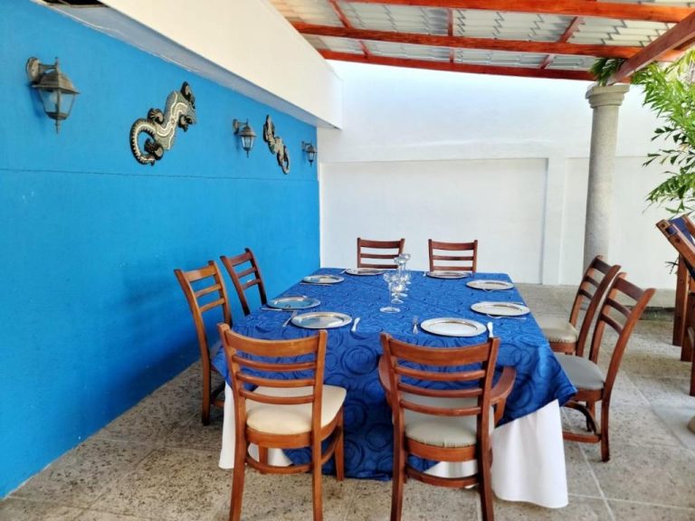 Terraza comedor exterior con mesa azul y decoración de dragones en Hotel Casa del Sol