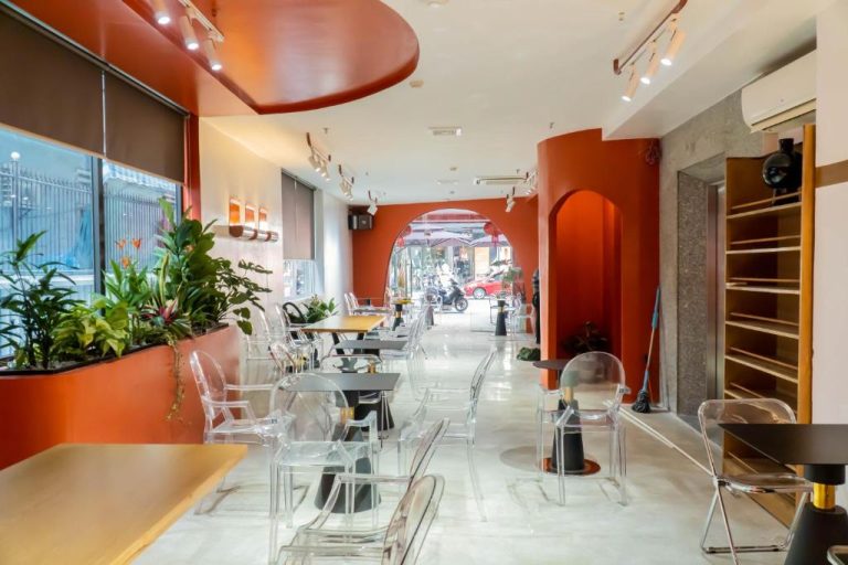 Restaurante interior moderno con sillas transparentes y paredes rojas del Quoc Cuong Hotel Danang by Haviland