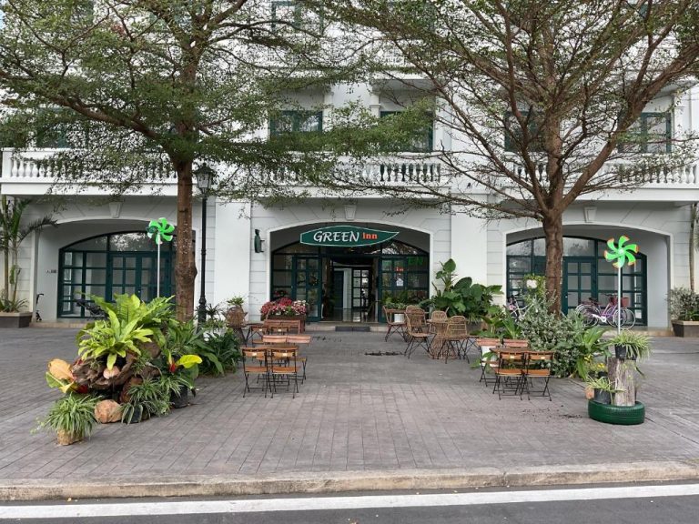 Fachada exterior del Green Inn Phu Quoc Hotel con terraza, mesas y jardín tropical