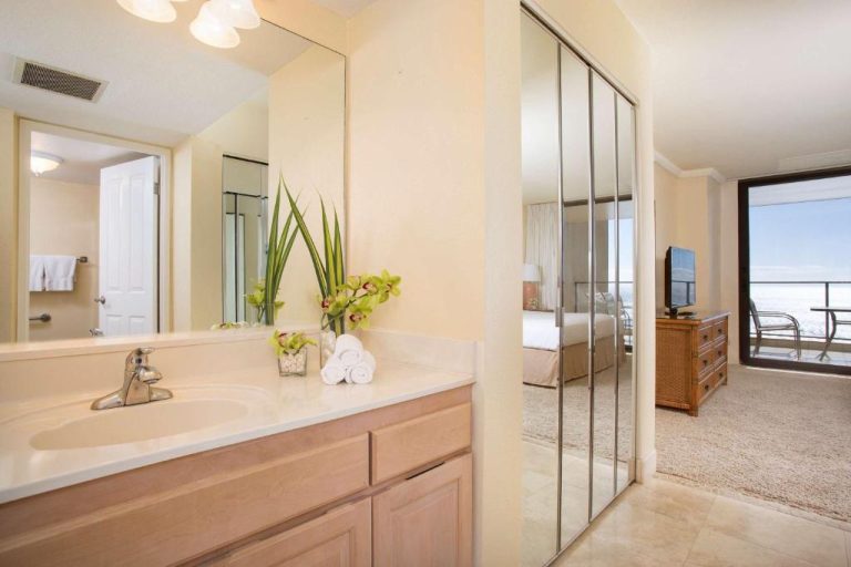 Baño con lavabo y espejo amplio en suite del Aston Mahana at Kaanapali con vistas al dormitorio y océano