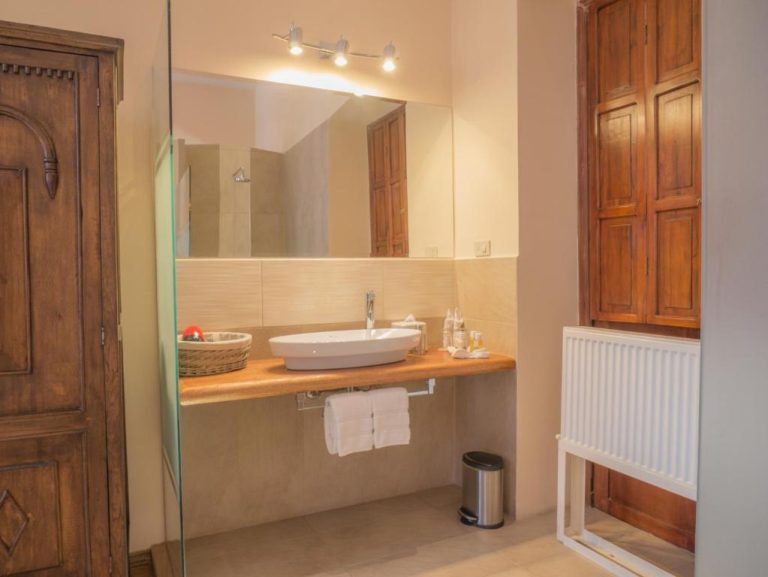 Baño privado con lavabo sobre encimera de madera y ducha acristalada en Casa El Edén