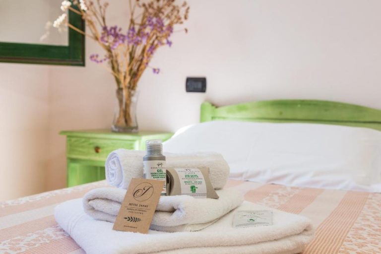 Toallas y amenities de bienvenida sobre la cama de una habitación del Hotel Janas en Marina di Sorpresa