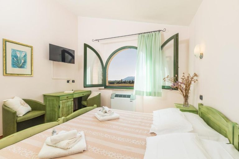 Habitación doble con decoración en verde y ventana arqueada con vistas al campo en Hotel Janas