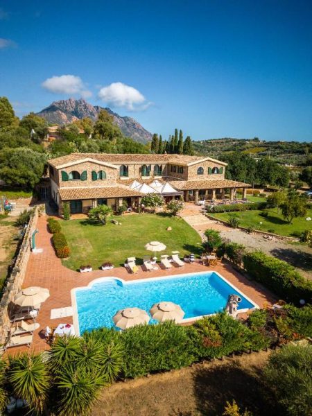 Vista aérea de la piscina exterior y jardín del Hotel Janas con montañas al fondo