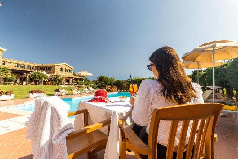 Mujer disfrutando de un cóctel en la terraza junto a la piscina exterior del Hotel Janas
