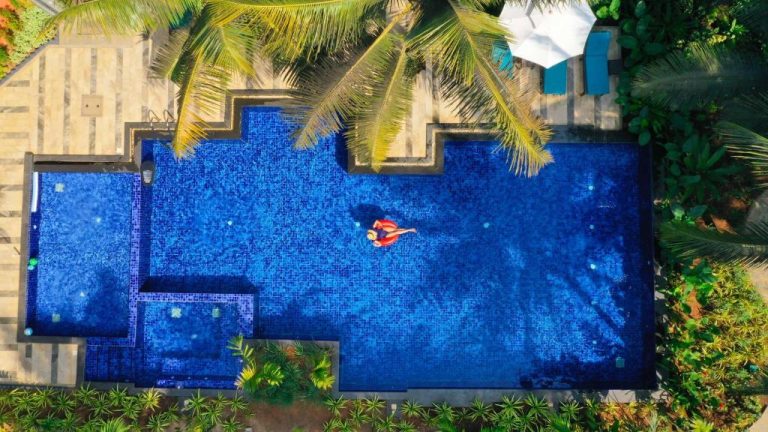 Vista aérea de la piscina exterior del Mandrem Beach Resort Radisson con palmeras tropicales en Goa