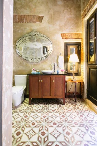 Baño boutique con azulejos artesanales y espejo veneciano en Villa Herencia Hotel