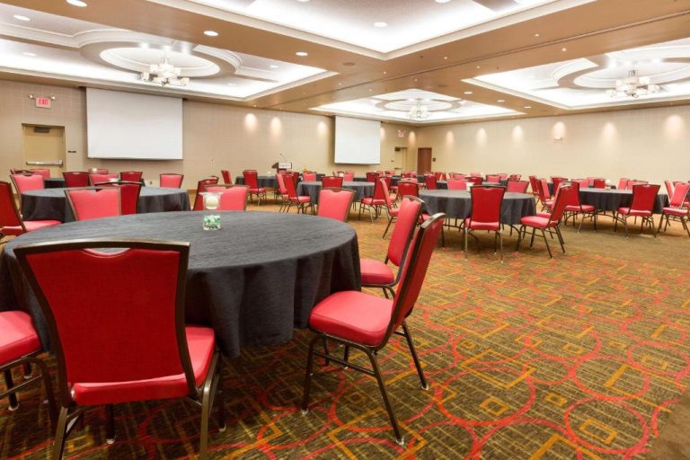 Salón de eventos con mesas redondas y sillas rojas en el Drury Plaza Hotel Indianapolis Carmel