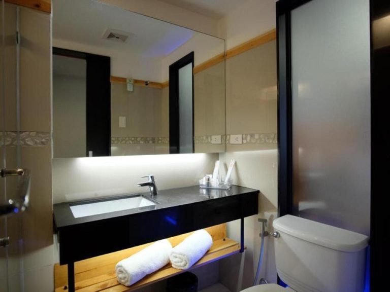 Baño moderno con lavabo empotrado y espejo amplio en Cuarto Hotels Cebu con toallas blancas