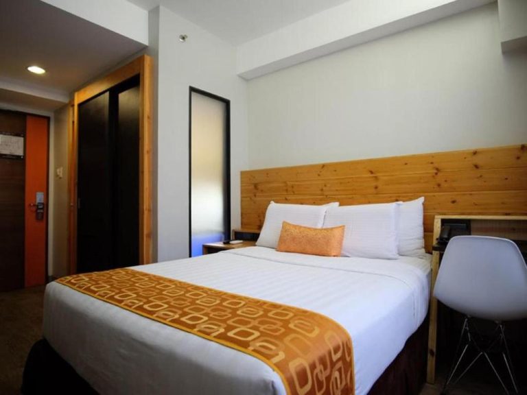 Habitación doble con cama matrimonial y cabecero de madera en Cuarto Hotels Cebu