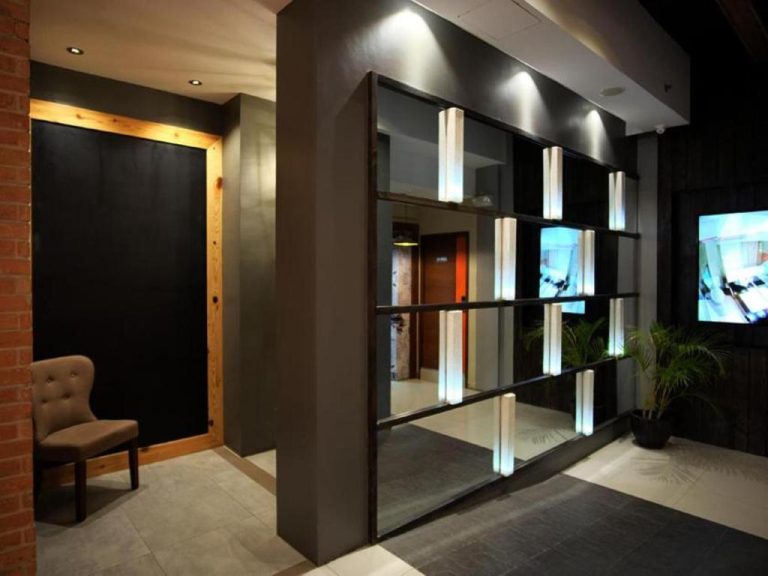 Lobby moderno con espejo decorativo iluminado y pantalla TV en Cuarto Hotels Cebu