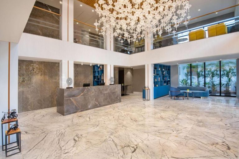 Lujoso lobby con suelo de mármol y gran araña de cristal en el Hyatt Place Goa Candolim