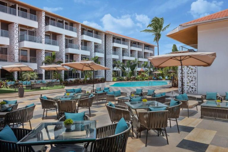 Terraza con mesas y sillas junto a la piscina exterior del Hyatt Place Goa Candolim