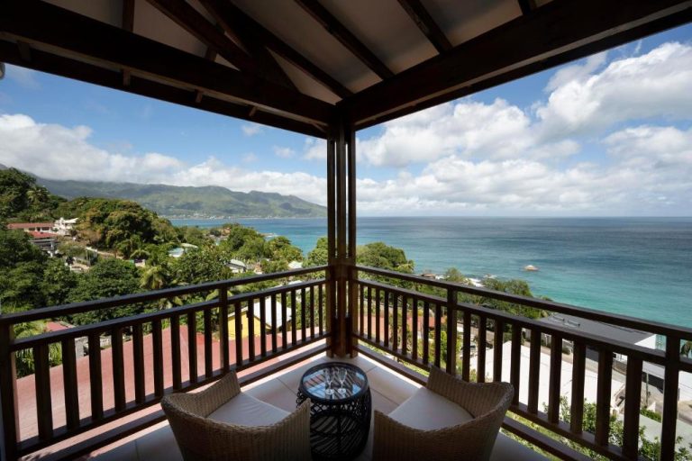 Terraza privada con sillas de mimbre y vistas panorámicas al océano en Sunbird Villas Seychelles