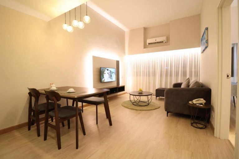Salón comedor moderno con sofá, mesa de madera y TV en Crown Regency Serviced Suites