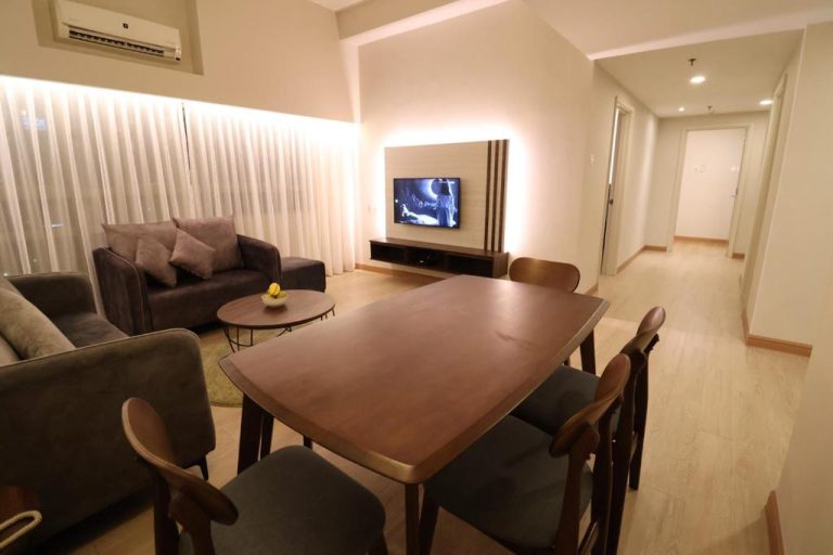 Salón comedor moderno con mesa de madera y televisor en Crown Regency Serviced Suites