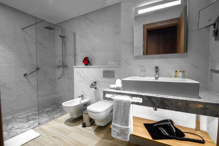 Baño de lujo con ducha, bidé y revestimiento de mármol blanco en el Hotel Dominium Palace