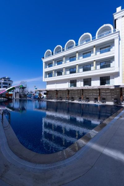 Piscina exterior con tumbonas y fachada blanca del Belenli Resort Hotel bajo cielo azul