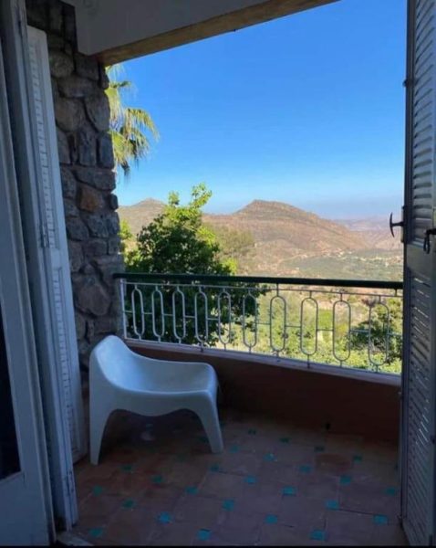 Balcón con silla blanca y vistas panorámicas a las montañas en Auberge des Cascades Imouzzer Paradise Valley