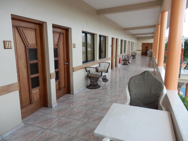 Corredor exterior con sillas de mimbre frente a habitaciones del Hotel Garant & Suites