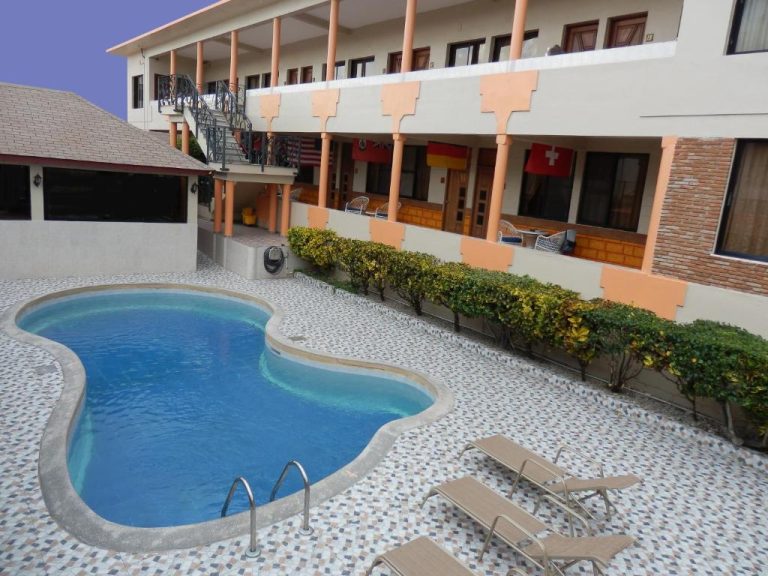 Piscina exterior con tumbonas y jardín del Hotel Garant & Suites con vistas a la fachada principal