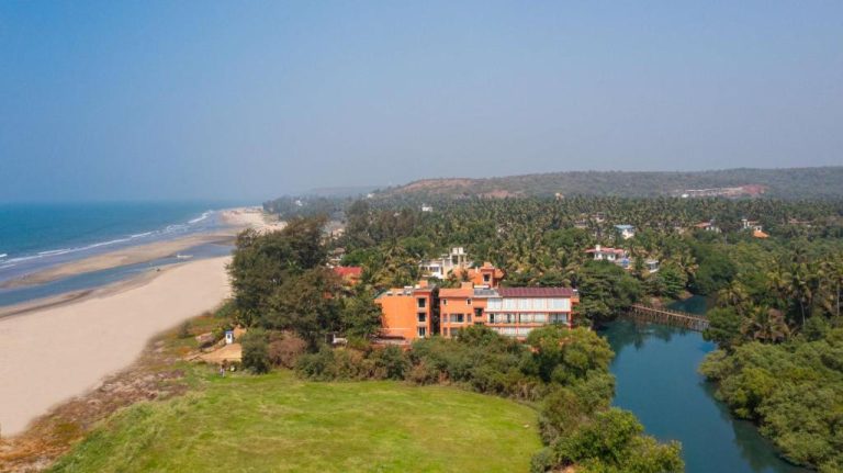 Vista aérea del Mandrem Beach Resort Radisson con playa virgen, río y vegetación tropical en Goa