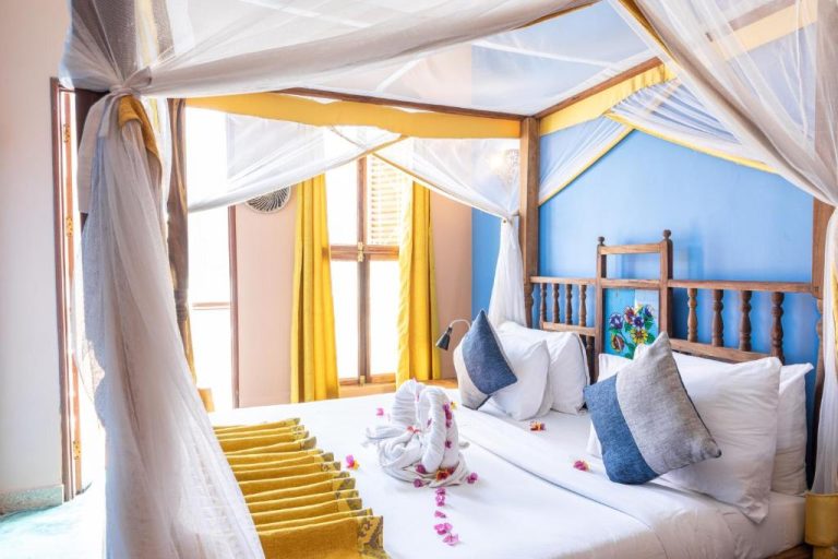 Habitación con cama de dosel y mosquitera blanca en Shaba Boutique Hotel, decoración azul y dorada
