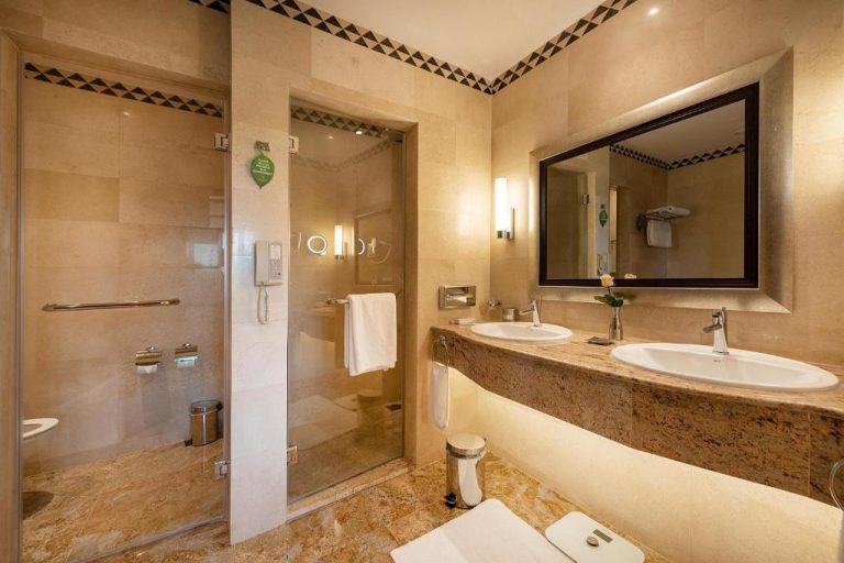 Baño de lujo con doble lavabo y ducha acristalada en mármol del Nairobi Serena Hotel