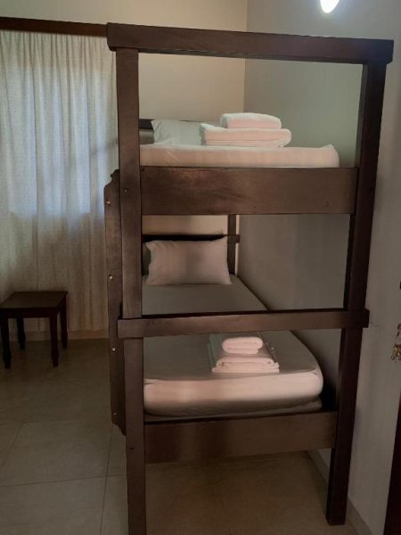 Habitación con literas de madera triples y ropa de cama blanca en Hotel Il Castello