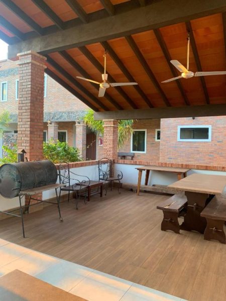 Terraza exterior con asador BBQ, mesas de madera y ventiladores de techo en Hotel Il Castello
