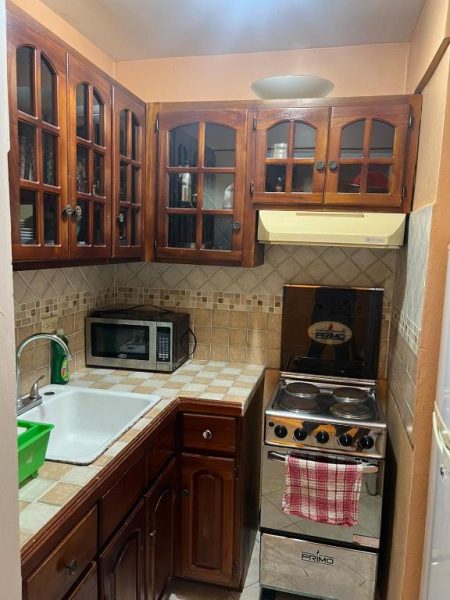 Cocina equipada con estufa, microondas y gabinetes de madera en Sunny Tides at Montego Bay Club Resort