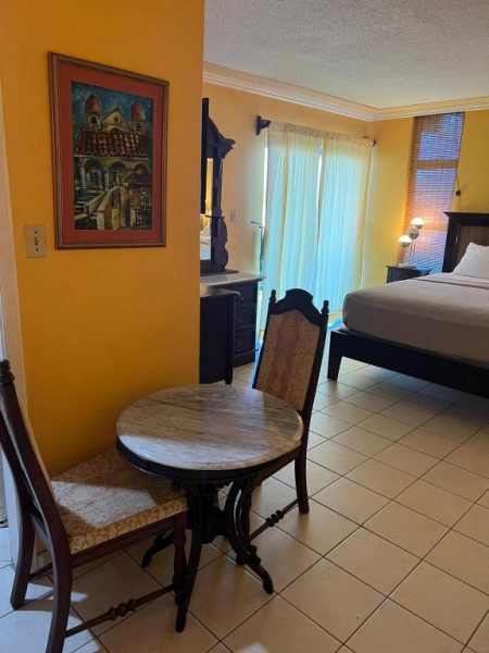 Habitación con cama doble, mesa de mármol y decoración caribeña en Sunny Tides Montego Bay Club Resort