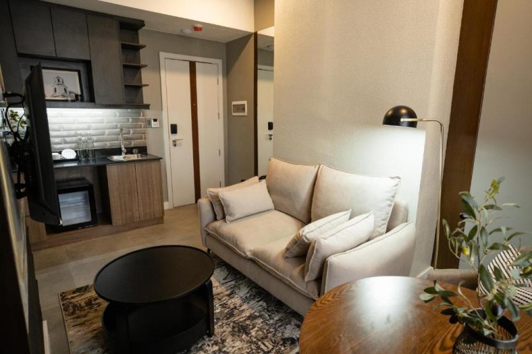 Sala de estar con sofá blanco y kitchenette moderna en la suite del Amber Hotel Cebu