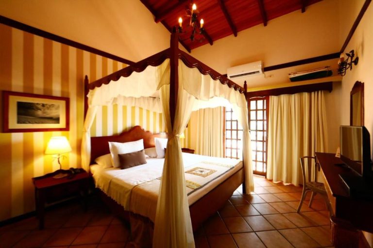 Habitación con cama de dosel y decoración colonial del Manary Praia Hotel en Natal, Brasil