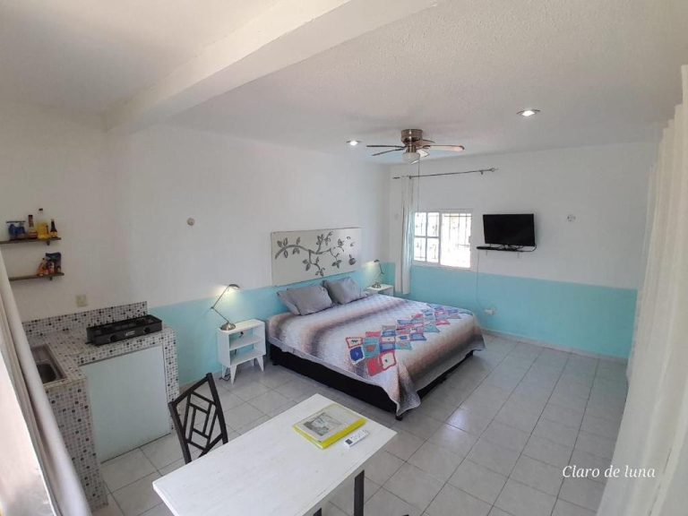 Estudio con cama doble, cocina equipada y paredes turquesa en el Hotel Claro de Luna