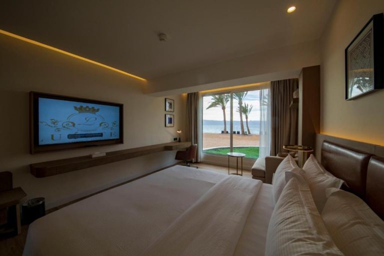 Habitación de lujo con cama doble, TV y vista al mar y playa en Luxotel Aqaba Beach Resort & Spa
