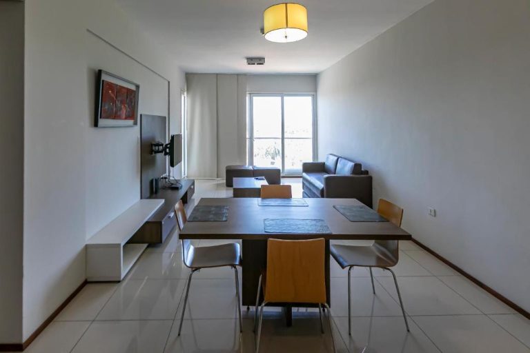 Salón comedor moderno con mesa para 4 personas y sofá en Asunción Rent Suites Santa Teresa