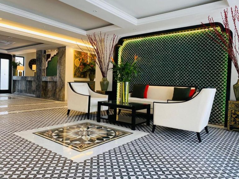 Elegante lobby del hotel The Leith con sofás blancos, suelo de mosaico y decoración en verde y negro