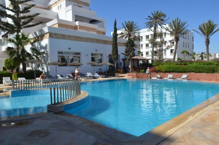 Piscina exterior con tumbonas y palmeras del Intouriste Hotel & Suites en Agadir, Marruecos