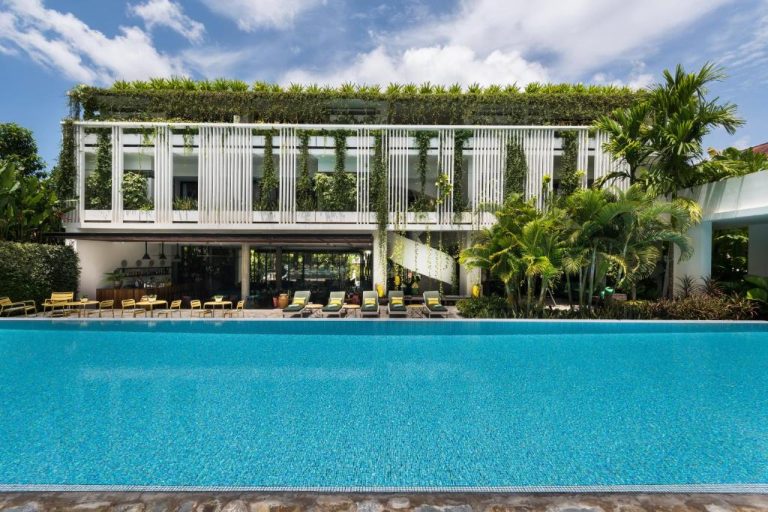 Piscina exterior con jardín vertical y tumbonas del Viroth's Hotel rodeada de vegetación tropical