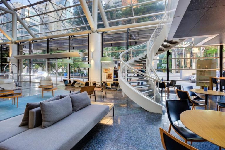 Lobby moderno con escalera espiral y zona de descanso del Radisson São Paulo Paulista