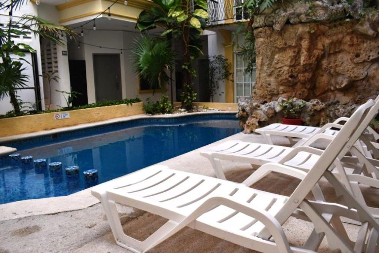 Piscina exterior con tumbonas blancas y vegetación tropical del Hotel Maya Turquesa en Playa del Carmen