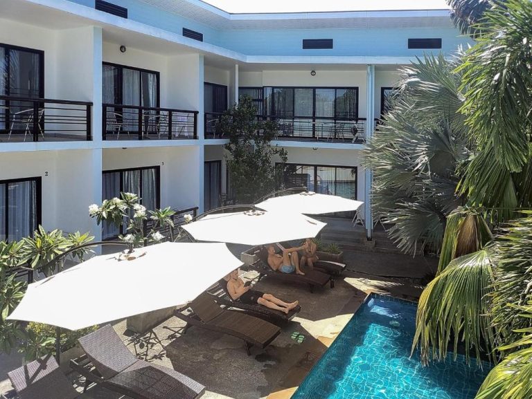 Piscina exterior con tumbonas y sombrillas blancas en Villa LunaSole Samui rodeada de palmeras