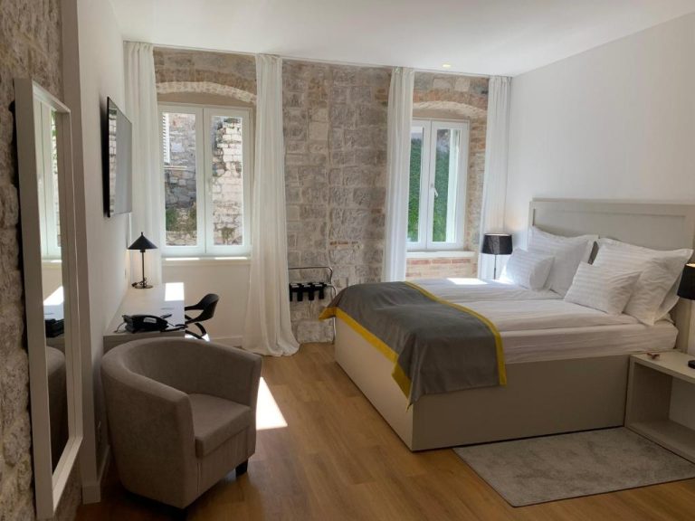 Habitación doble con pared de piedra histórica y cama king en Priuli Heritage Suites