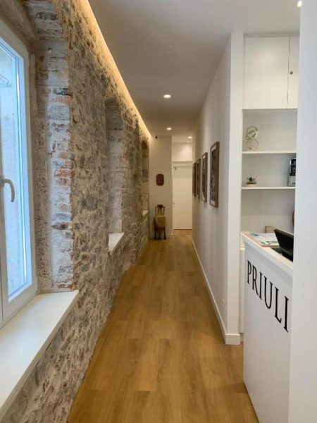 Pasillo interior con pared de piedra histórica y suelo de madera en Priuli Heritage Suites